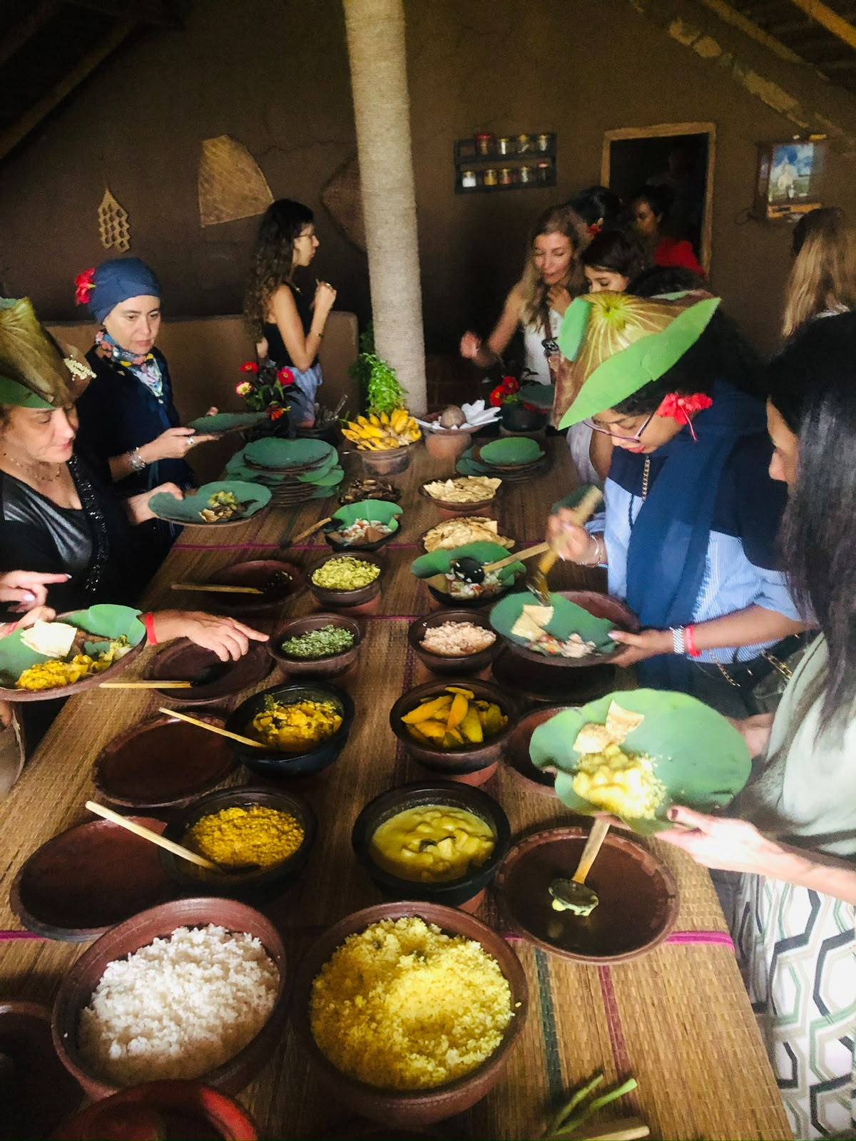 Guests serving village curries onto lotus-leaf plates